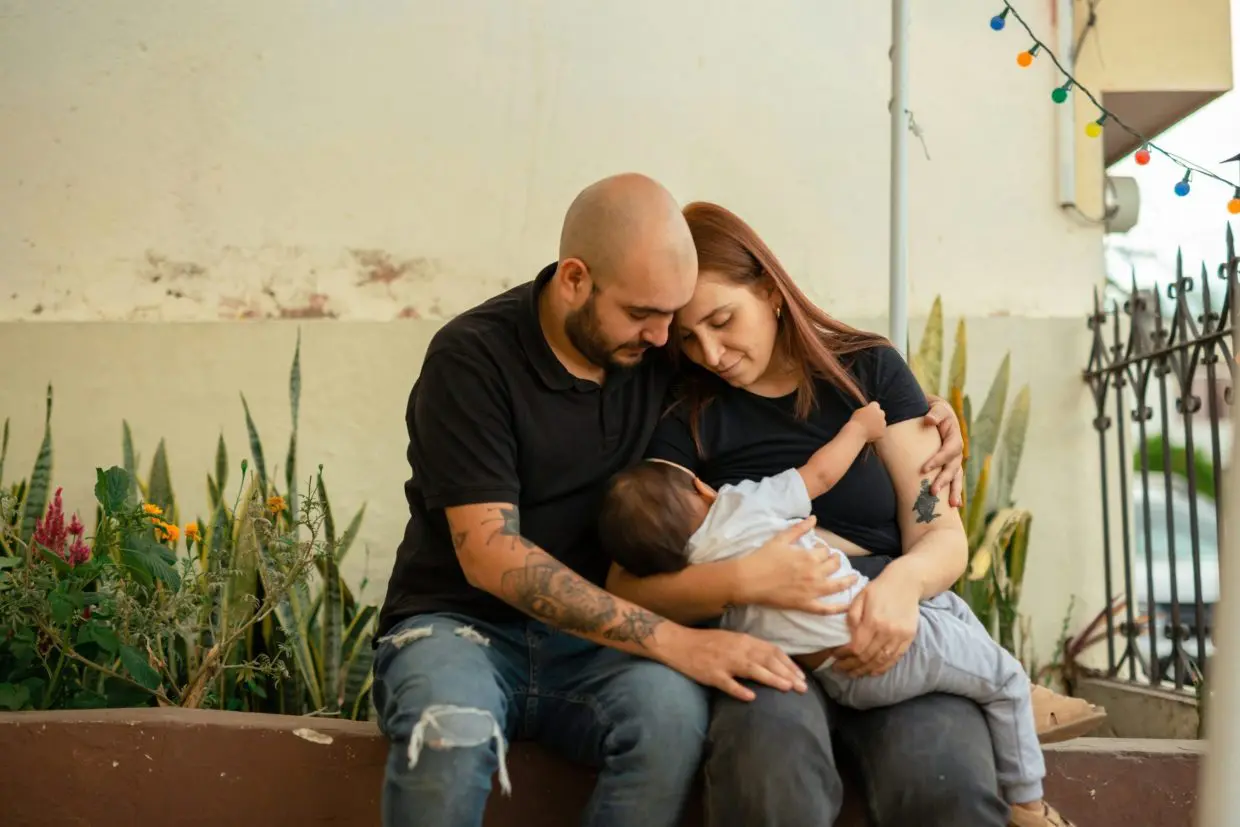 Hombre y mujer sosteniendo en su regazo a su hijo. Terapia perinatal y de pareja online